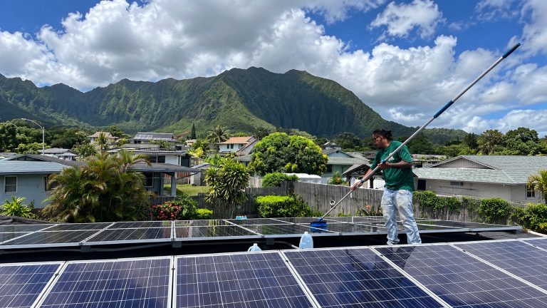 Technician cleaning solar panels on an Oahu home